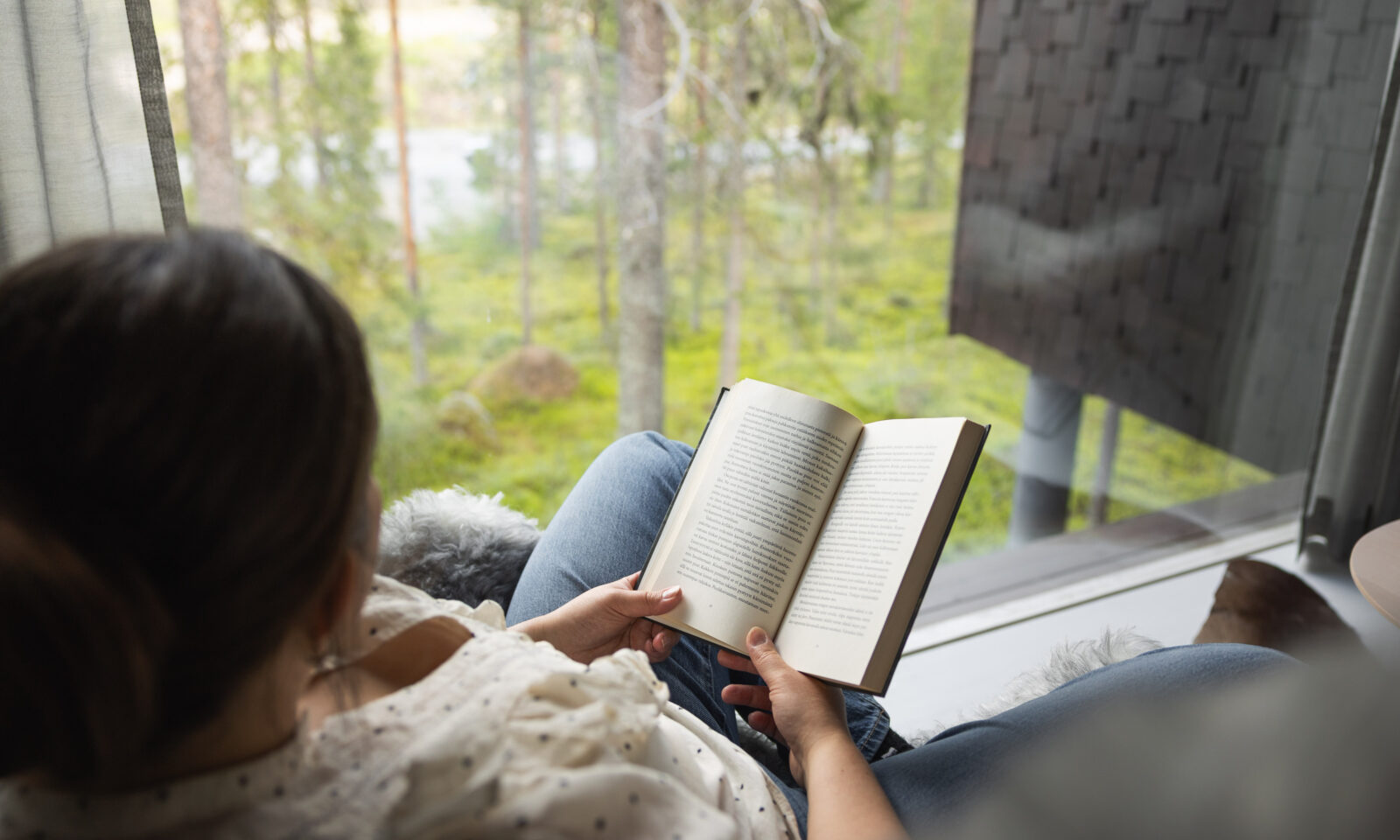 woman reading in arctic treehouse suite in summer. Rovaniemi, Lapland.